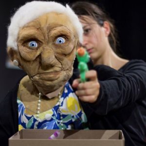 une marionnette de vieille dame brandit un pistolet à eau